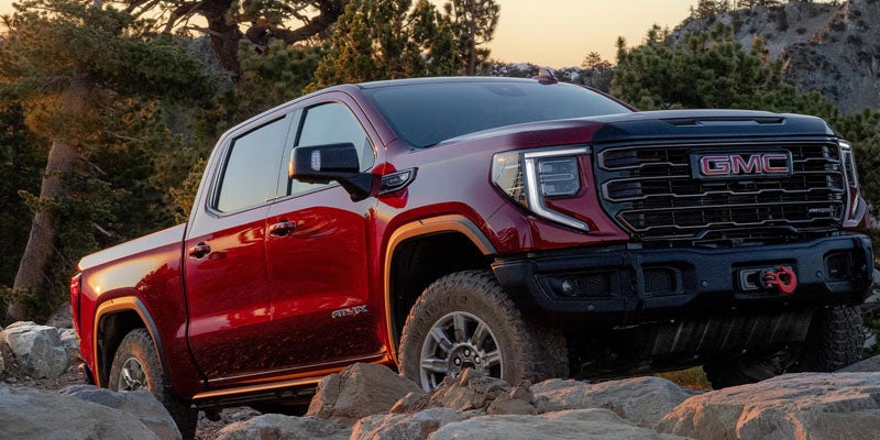 Red 2026 GMC Sierra 1500 climbing over rocky terrain
